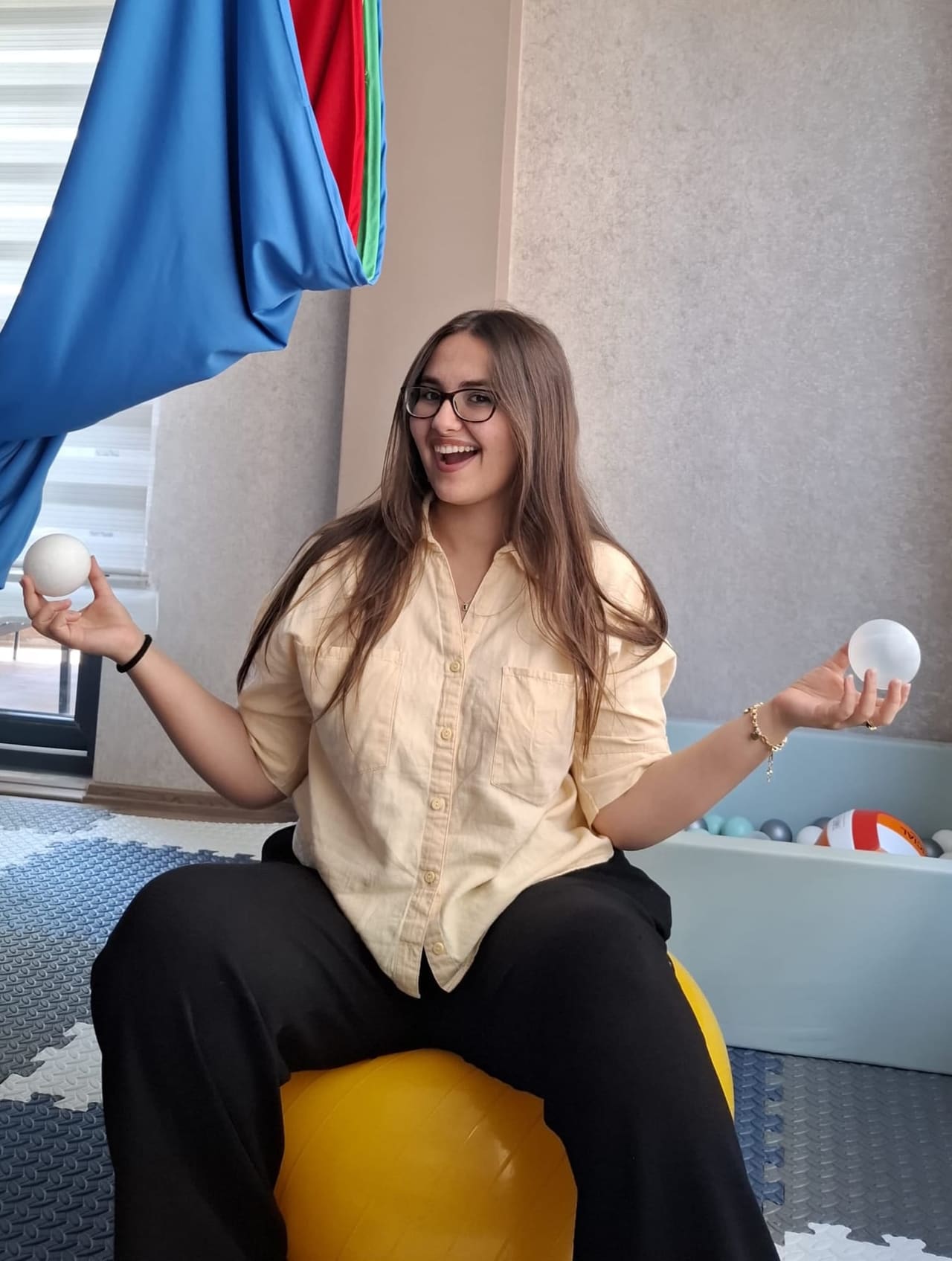 Dkt. Ayşe Türedi, terapi odasında denge topunun üzerinde otururken